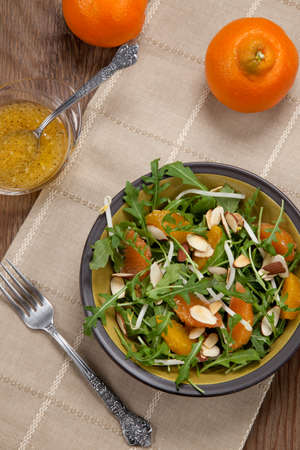 Closeup of a plate of arugula salad with mandarins oranges beans sprouts and sliced almonds served with mandarin vinaigrette for healthy lunch.の写真素材