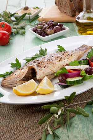 Mediterranean style organic roasted whole sea bass garnished with Greek salad.の写真素材
