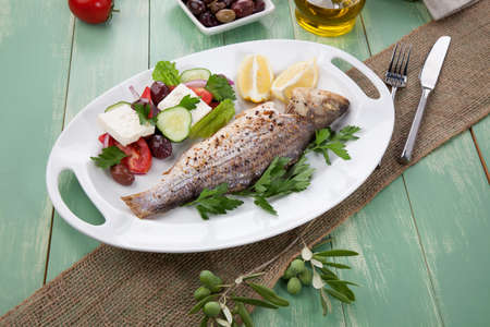 Mediterranean style organic roasted whole sea bass garnished with Greek salad.の写真素材