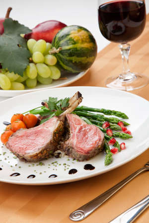 Herb crusted lamb chops ribs garnished with asparagus carrots and pomegranates. Mini pumpkins and fresh fruitsの写真素材