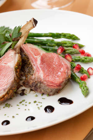 Herb crusted lamb chops ribs garnished with asparagus carrots and pomegranates. Mini pumpkins and fresh fruitsの写真素材