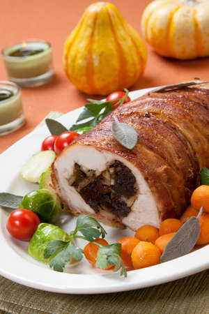 Delicious baconwrapped turkey breast roulade garnished with Brussels sprouts tomatoes and Parisian carrots.の写真素材
