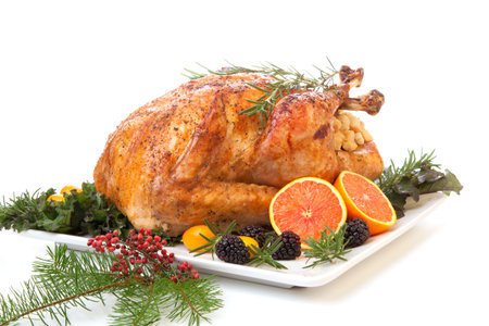 Roasted stuffed turkey garnished with fresh fruits and herbs for holiday dinner.の写真素材