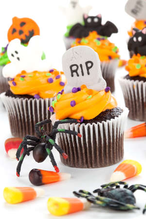 Halloween cupcake with RIP, ghost, and bat decorations surrounded by Halloween cupcakes, corn candies, and decoration.の写真素材