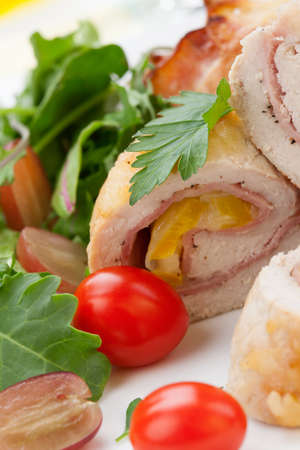 Tasty chicken prosciutto roulade stuffed with cheese and pineapple, served with baby kale, grapes, and cherry tomatoes salad.の写真素材