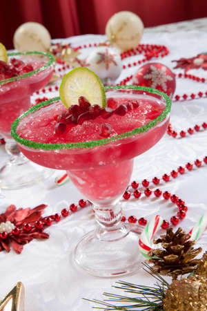 Two frozen pomegranate margaritas cocktails on Christmas decorated holiday table with Christmas ornaments. Holiday cocktails series.の写真素材