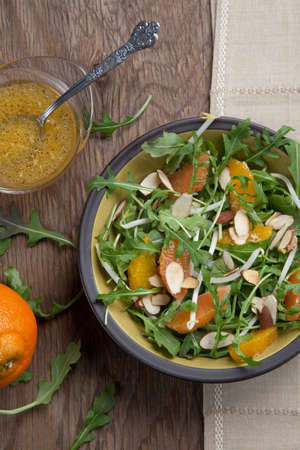 Closeup of a plate of arugula salad with mandarins, oranges, beans sprouts, and sliced almonds served with mandarin vinaigrette for healthy lunch.の写真素材