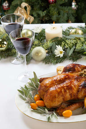 Citrus glazed roasted duck stuffed with rice, garnished with apples, kumquats, and sage. Christmas decorated setting.の写真素材