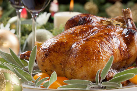 Citrus glazed roasted duck stuffed with rice, garnished with apples, kumquats, and sage. Christmas decorated setting.の写真素材