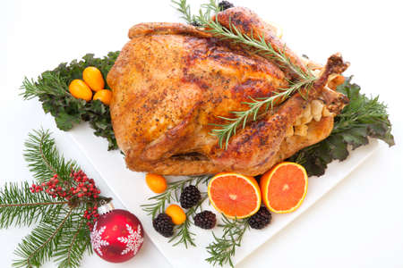 Roasted stuffed turkey garnished with fresh fruits and herbs for holiday dinner.の写真素材