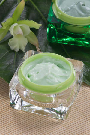 Closeup gorgeous blooming green colored Cattleyas orchid flowers and jars of cosmetics cream.の写真素材