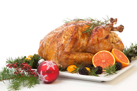 Roasted stuffed turkey garnished with fresh fruits and herbs for holiday dinner.の写真素材