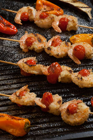 Grilled Parmesan crust shrimp with chery tomatoes on the grill with grilled mini bell peppers.の写真素材