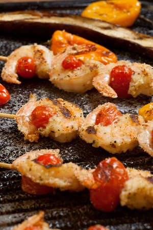 Grilled Parmesan crust shrimp with chery tomatoes on the grill with grilled mini bell peppers.の写真素材