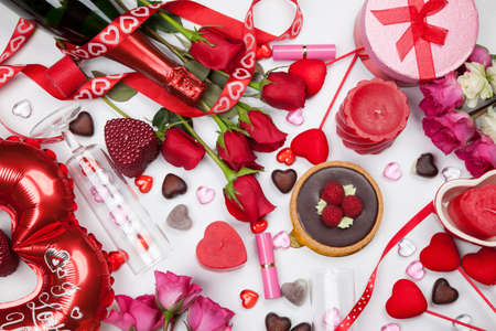 Close up of Valentine Day assortiment of different gifts, candies, red roses, cosmetics, candles, and bottle of Champagne.の写真素材