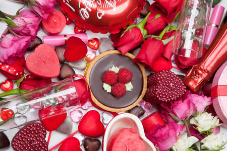 Close up of Valentine Day assortiment of different gifts, candies, red roses, cosmetics, candles, and bottle of Champagne.の写真素材