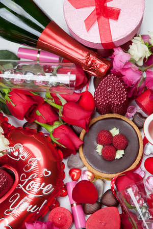 Close up of Valentine Day assortiment of different gifts, candies, red roses, cosmetics, candles, and bottle of Champagne.の写真素材