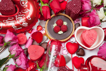 Close up of Valentine Day assortiment of different gifts, candies, red roses, cosmetics, candles, and bottle of Champagne.の写真素材