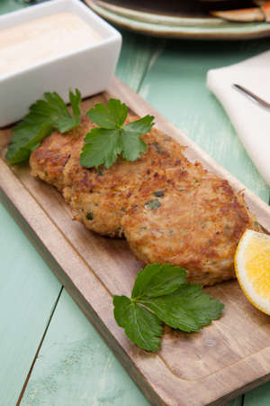 Three crab cakes appetizer with spicy sauce and fresh parsley. Dungeness crab in the background.の写真素材
