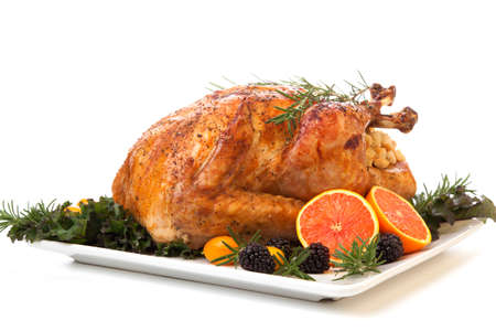 Roasted stuffed turkey garnished with fresh fruits and herbs for holiday dinner.の写真素材