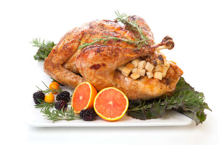 Roasted stuffed turkey garnished with fresh fruits and herbs for holiday dinner.の写真素材
