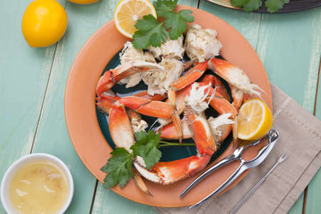 Assorted Dungeness crab legs with butter mustard sauce and fresh lemons.の写真素材