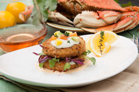 Crab cakes appetizer with two sauces, baby greens, and mango - avocado citrus salsa. Dungeness crab in the background.の写真素材