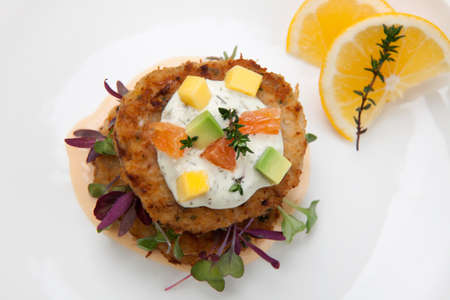 Crab cakes appetizer with two sauces, baby greens, and mango - avocado citrus salsa. Dungeness crab in the background.の写真素材