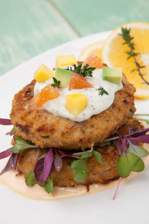 Crab cakes appetizer with two sauces, baby greens, and mango - avocado citrus salsa. Dungeness crab in the background.の写真素材