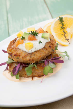 Crab cakes appetizer with two sauces, baby greens, and mango - avocado citrus salsa. Dungeness crab in the background.の写真素材