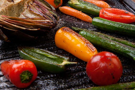 Assorted grilled vegetables - zucchini, asparagus, artichokes, mini pepper, jalapeno, tomatoes, and carrots - on griddle.の写真素材