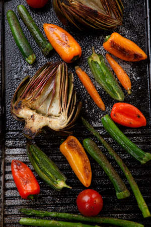 Assorted grilled vegetables - zucchini, asparagus, artichokes, mini pepper, jalapeno, tomatoes, and carrots - on griddle.の写真素材