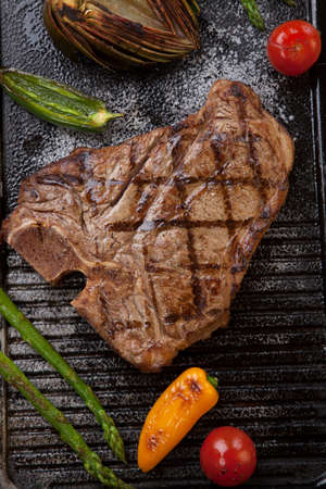 Summer grill - grilled sausages and T-bone steak - on griddle.の写真素材