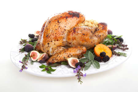 Glazed roasted turkey on serving tray over white background. Garnished with figs, blackberry, persimmon, sage, and basil.の写真素材