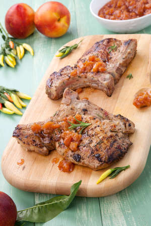 Grilled pork chops with nectarine - pepper chutney. Fresh nectarines and hot pepper.の写真素材