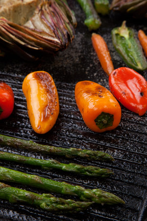 Assorted grilled vegetables - zucchini, asparagus, artichokes, mini pepper, jalapeno, tomatoes, and carrots - on griddle.の写真素材