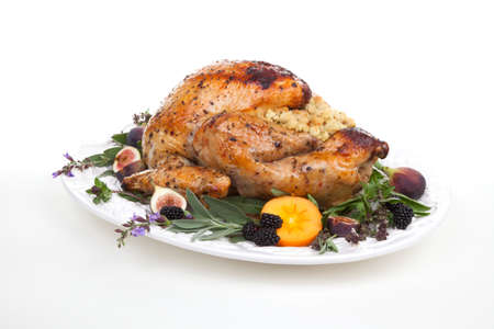 Glazed roasted turkey on serving tray over white background. Garnished with figs, blackberry, persimmon, sage, and basil.の写真素材