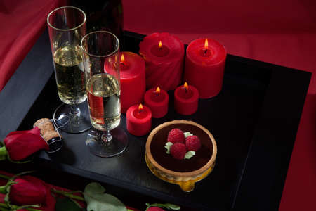 Celebration tray for Valentines Day - Champagne, chocolate raspberry cake, candles, and red roses.の写真素材