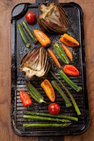 Assorted grilled vegetables - zucchini, asparagus, artichokes, mini pepper, jalapeno, tomatoes, and carrots - on griddle.の写真素材