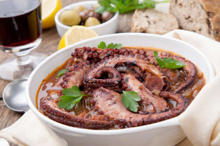 Bowl of delicious octopus and red wine stew - traditional Mediterranean dish. Fresh bread, olives, and red wine.の写真素材