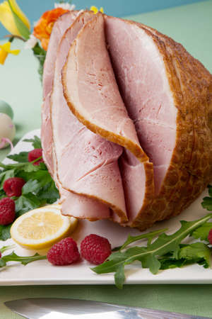 Easter themed prepared sliced honey ham and fresh raspberry, arugula, lemons, Ester eggs decoration. Spring flowers and pink wine.の写真素材