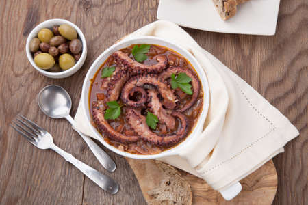 Bowl of delicious octopus and red wine stew - traditional Mediterranean dish. Fresh bread, olives, and red wine.の写真素材