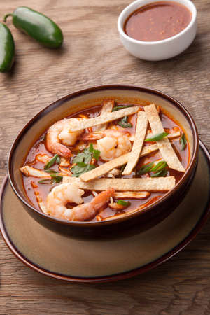 Bowl of hot delicious shrimp tortilla soup garnished with green onion, fresh cilantro, and salsa.の写真素材