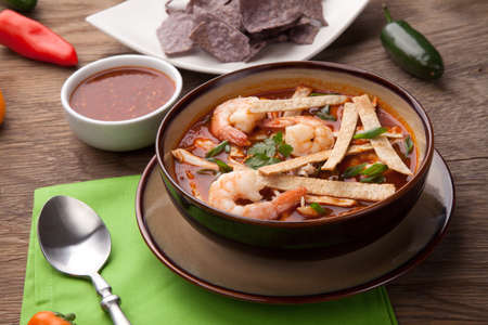 Bowl of hot delicious shrimp tortilla soup garnished with green onion, fresh cilantro, and salsa.の写真素材