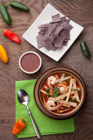 Bowl of hot delicious shrimp tortilla soup garnished with green onion, fresh cilantro, and salsa.の写真素材