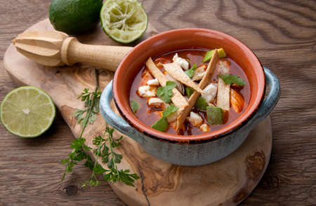 Bowl of hot delicious spicy chicken tortilla soup garnished with crumbled queso fresco cheese, diced avocado, and fresh cilantro.の写真素材