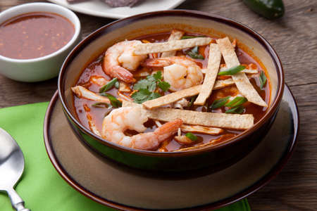 Bowl of hot delicious shrimp tortilla soup garnished with green onion, fresh cilantro, and salsa.の写真素材