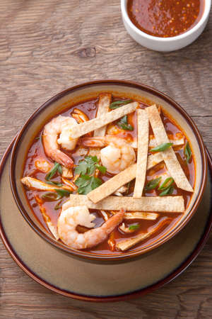 Bowl of hot delicious shrimp tortilla soup garnished with green onion, fresh cilantro, and salsa.の写真素材
