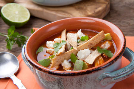 Bowl of hot delicious spicy chicken tortilla soup garnished with crumbled queso fresco cheese, diced avocado, and fresh cilantro.の写真素材