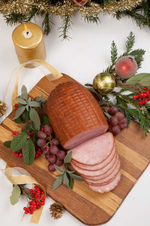 Roasted ham with fresh thyme for Christmas party. XMas tree in the background, surrounded by ornaments. Rustic style.の写真素材